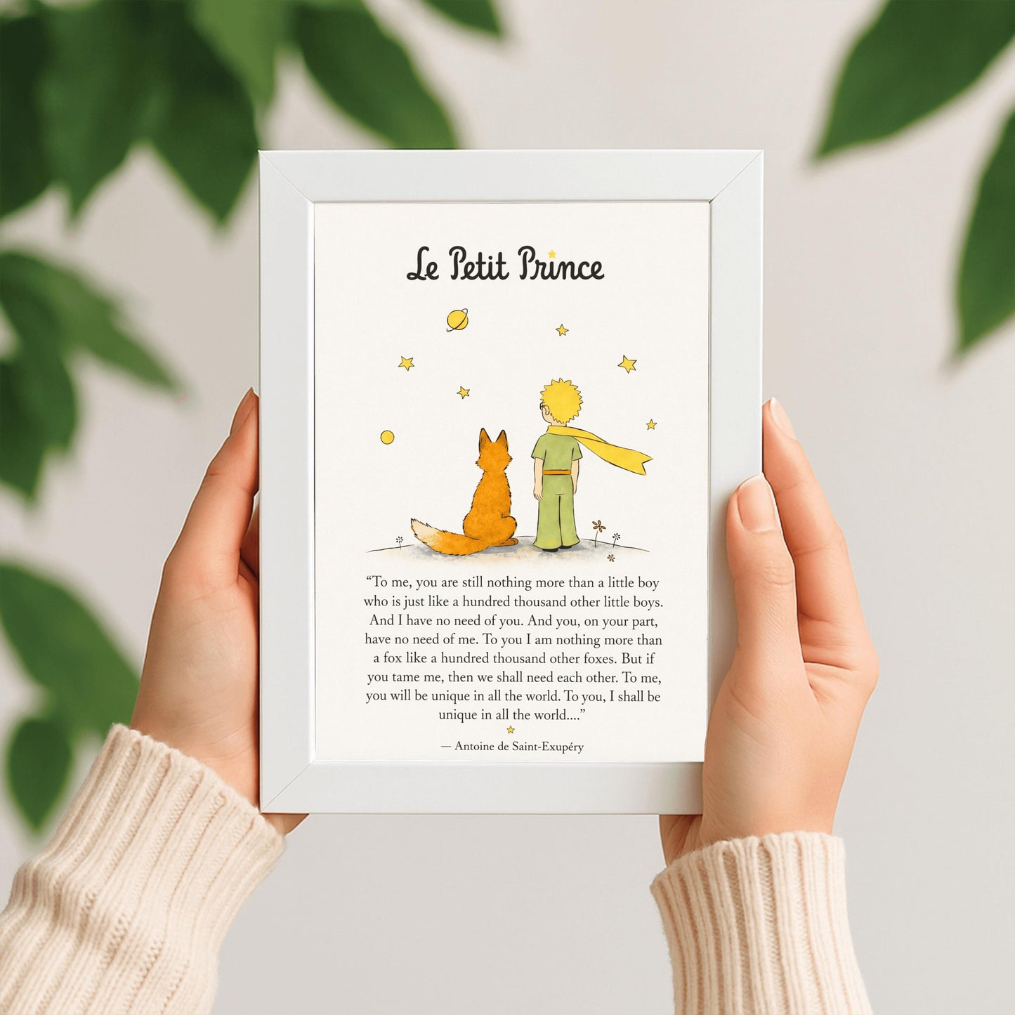 A vertical art print featuring a minimalist illustration of the Little Prince and the Fox from behind. The Prince wears a green suit and a long, flowing yellow scarf, standing next to an orange fox on a small grey mound. Above them are several simple yellow stars and a ringed planet. Below the illustration is a famous quote about "taming" and uniqueness from the book, attributed to Antoine de Saint-Exupéry.