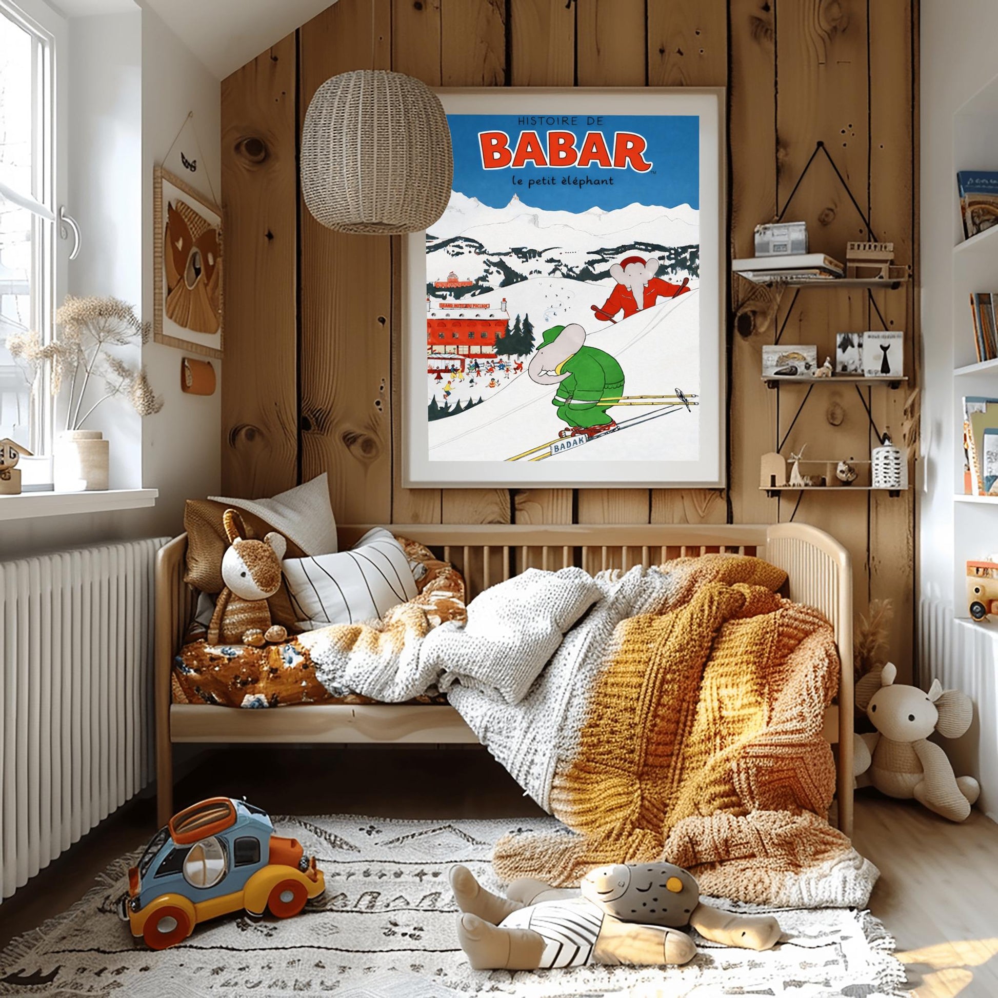 A vertical children's illustration poster titled "HISTOIRE DE BABAR le petit éléphant" in red. Two elephants are skiing down a snowy mountain slope. One is in a green suit in the foreground, and another is in a red suit behind him. In the background is a large red building labeled "GRAND HOTEL DU PAQUID" next to an outdoor ice rink with many small figures. Snow-capped mountains rise under a dark blue sky.