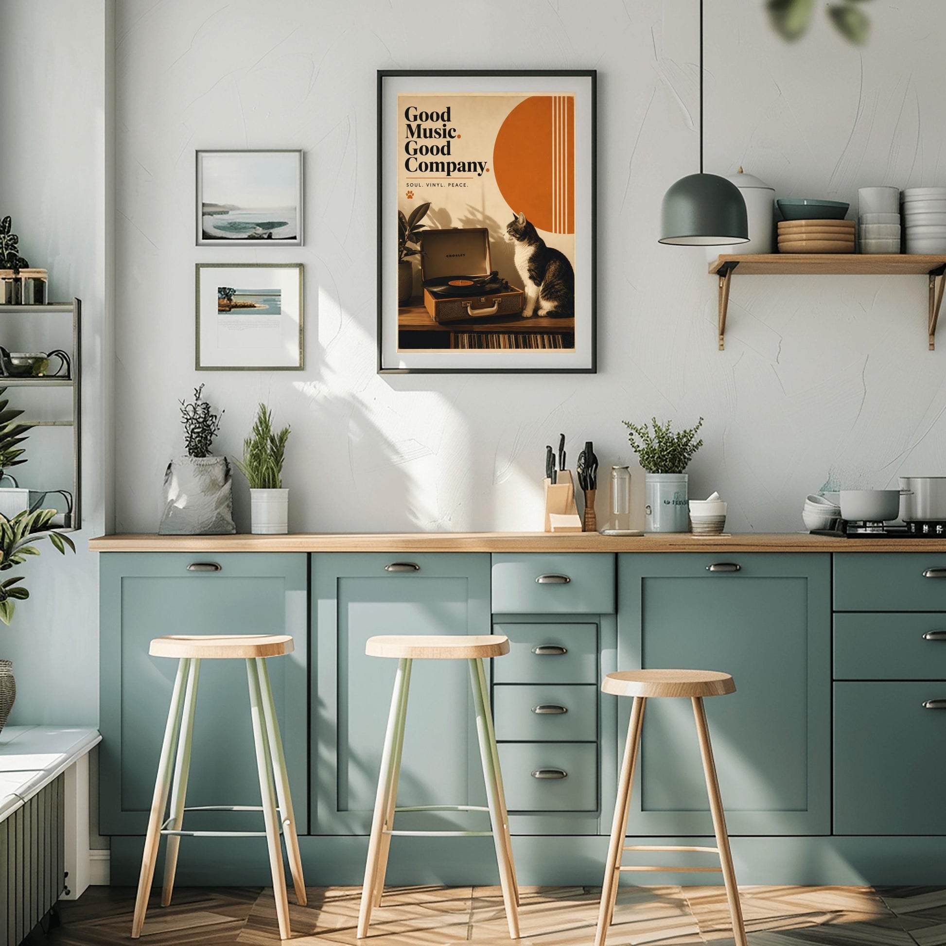 A vertical retro fine art poster titled "Good Music. Good Company." on a wide cream border. The design features a bold black serif heading on the left above the text "SOUL. VINYL. PEACE." and a small orange paw print. In the central artwork, a black and white tuxedo cat sits contentedly next to an open tan Crosley record player spinning a vinyl record. A large orange sun shape with white vertical stripes and a potted rubber plant decorate the background.