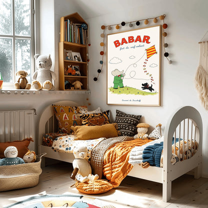 A vertical retro fine art exhibition poster titled "BABAR fait du cerf-volant" on a wide cream border. The top "BABAR" text is printed in a bold red font. The illustration shows an elephant in a green suit and red bowtie flying a red and yellow striped diamond kite on a green grassy hill with small flowers. A small black dog in a plaid scarf runs on the hill below, and the name "Laurent de Brunhoff" anchors the bottom.