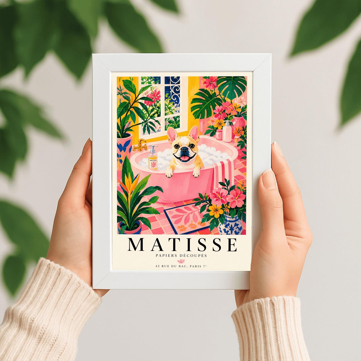 A vertical maximalist art print styled as a Henri Matisse exhibition poster. A tan and white French Bulldog with a wide, happy smile sits in a pink bathtub filled with white bubbles. The bathroom is vibrant with pink tiled floors, yellow walls, and a large window looking out onto a garden. The scene is filled with tropical plants like Monstera and Birds of Paradise. Bold black text at the bottom reads "MATISSE PAPIERS DÉCOUPÉS" with a Paris gallery address.