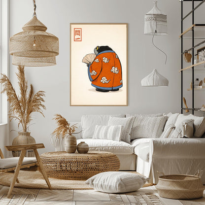 A vertical Japanese woodblock-style art print of a large, dark grey-black frog seen from behind. The frog is wearing an ornate burnt orange kimono decorated with white cloud motifs and blue piping. It holds a beige folding fan in its small hand. In the top left corner is a red rectangular stamp containing Japanese calligraphy. The entire image is set against a textured, pale cream background in a minimalist aesthetic.