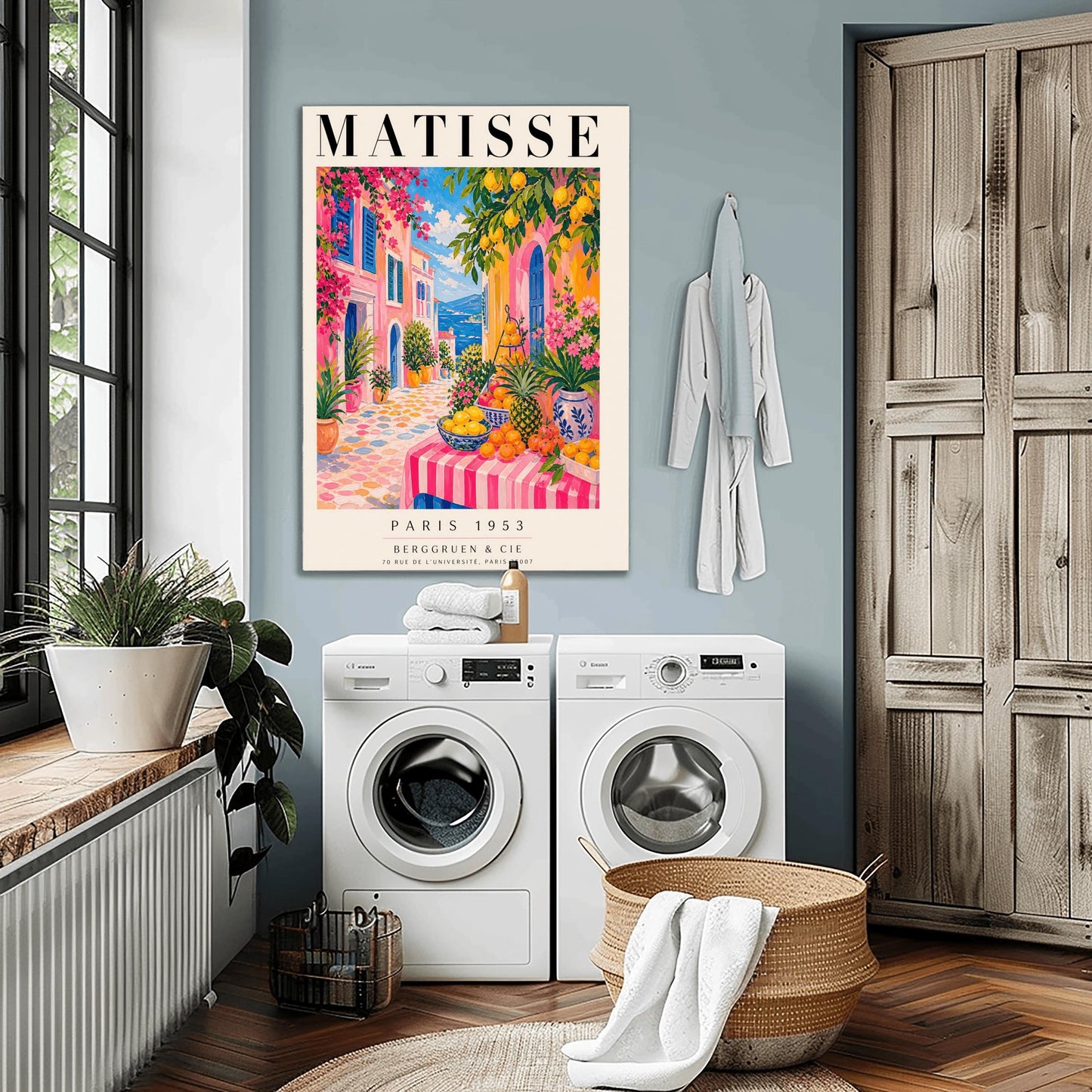 A vertical maximalist art print styled as a Henri Matisse exhibition poster. The scene depicts a vibrant, colorful street in a Mediterranean coastal town. In the foreground, a table with a pink and white striped cloth is piled high with lemons, oranges, and a pineapple. Hot pink and yellow buildings with blue shutters line a cobblestone path that leads toward a blue sea under a bright sky. Lush green trees with yellow lemons and pink flowers frame the view.