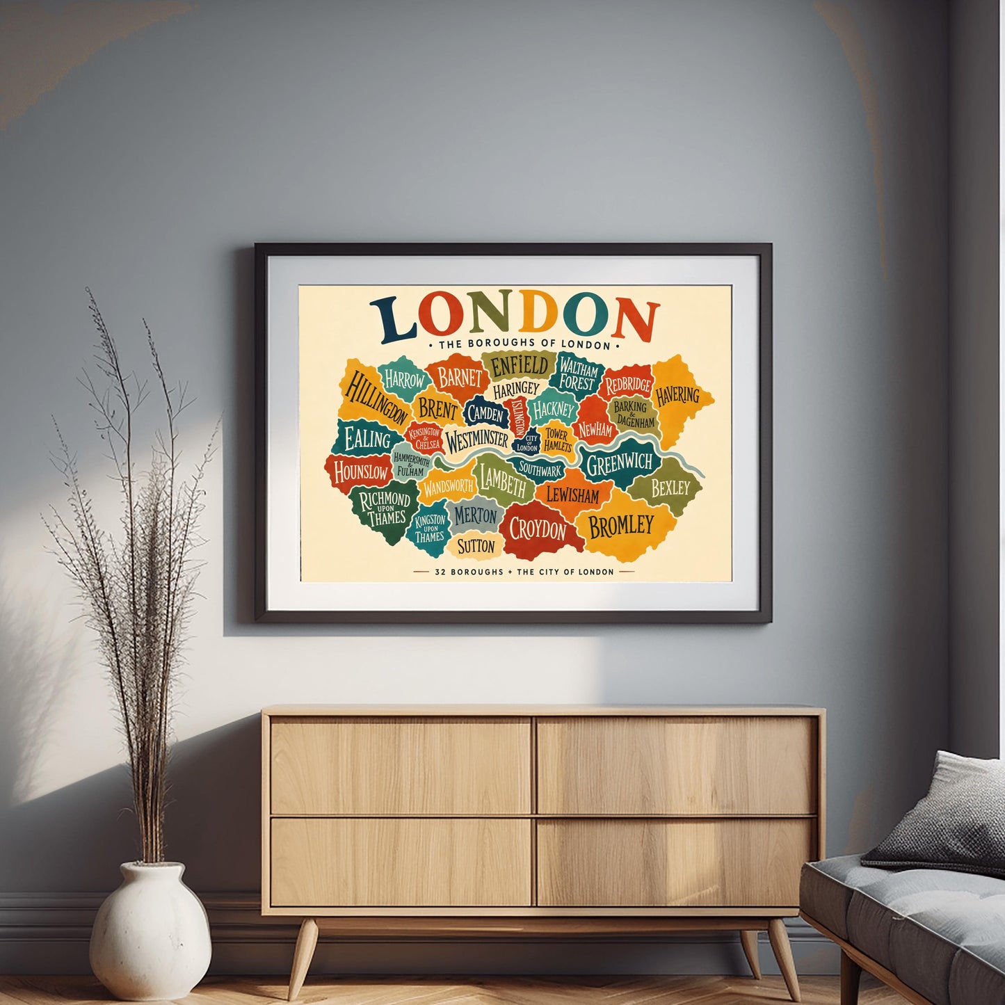 A horizontal vintage-style fine art exhibition poster mapping the boroughs of London. Set on a warm cream background with a wide border, the poster features a colorful, interlocking map of London's districts in shades of teal, orange, green, and yellow, with the River Thames running through the middle. A large, multicolored heading at the top reads "LONDON" and text at the bottom reads "32 BOROUGHS + THE CITY OF LONDON".