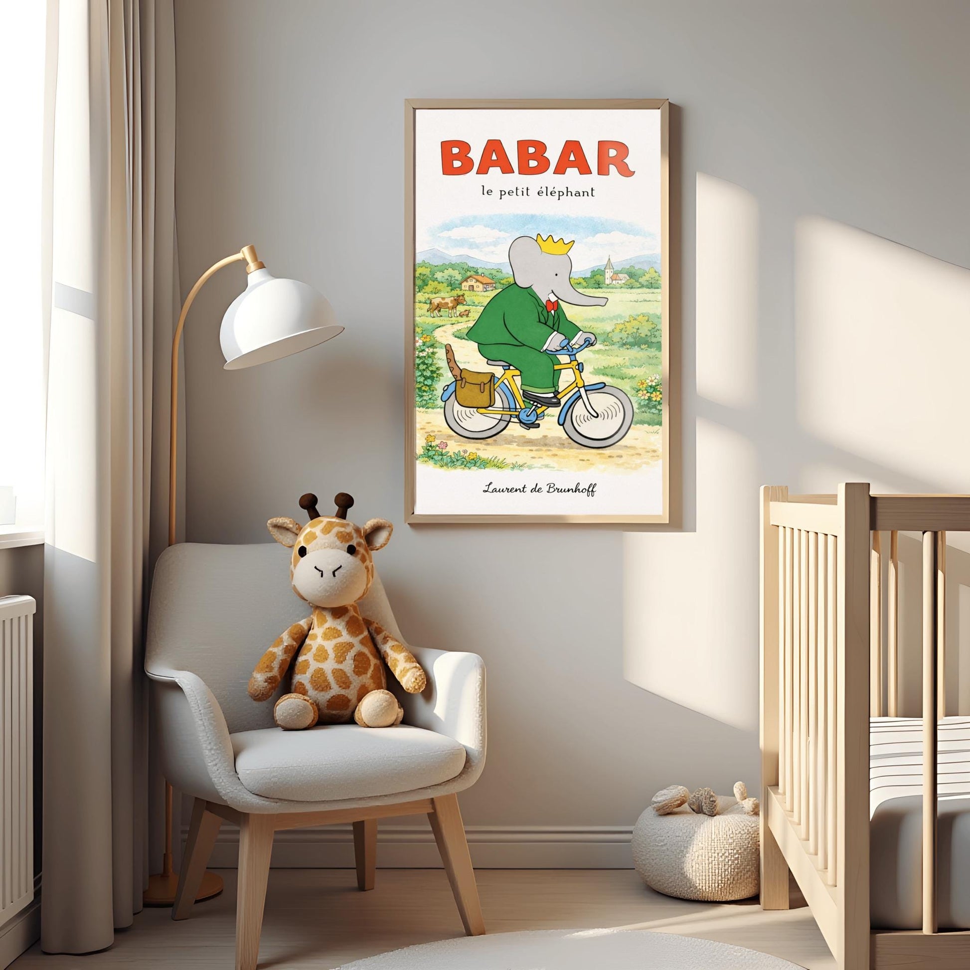 A vertical children's illustration poster titled "BABAR le petit éléphant" at the top in red. King Babar, in a green suit and crown, is riding a yellow bicycle along a dirt path. A brown leather bag on the back of the bike holds a baguette. The background shows a green meadow with a cow and calf, small bushes with flowers, and a distant house and church under a soft sky. The name "Laurent de Brunhoff" is at the bottom.