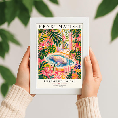 A vertical maximalist art print designed as a Henri Matisse exhibition poster. A large, grey manatee floats peacefully in a white bathtub filled with water. The room is filled with vibrant pink walls, lush green tropical plants, and bright pink hibiscus flowers. An open balcony door in the background shows a Parisian-style wrought-iron railing and pink flowers. Two colorful soap bottles sit on the edge of the tub.