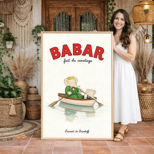 A vertical retro fine art exhibition poster titled "BABAR fait du canotage" on a wide cream border. The top "BABAR" text is printed in a bold red font. The illustration shows an elephant wearing a crown and green suit sitting in a white wooden rowboat with a red rim, holding two oars. A smaller elephant leans over the front of the boat looking at its reflection in the calm water. The name "Laurent de Brunhoff" anchors the bottom.