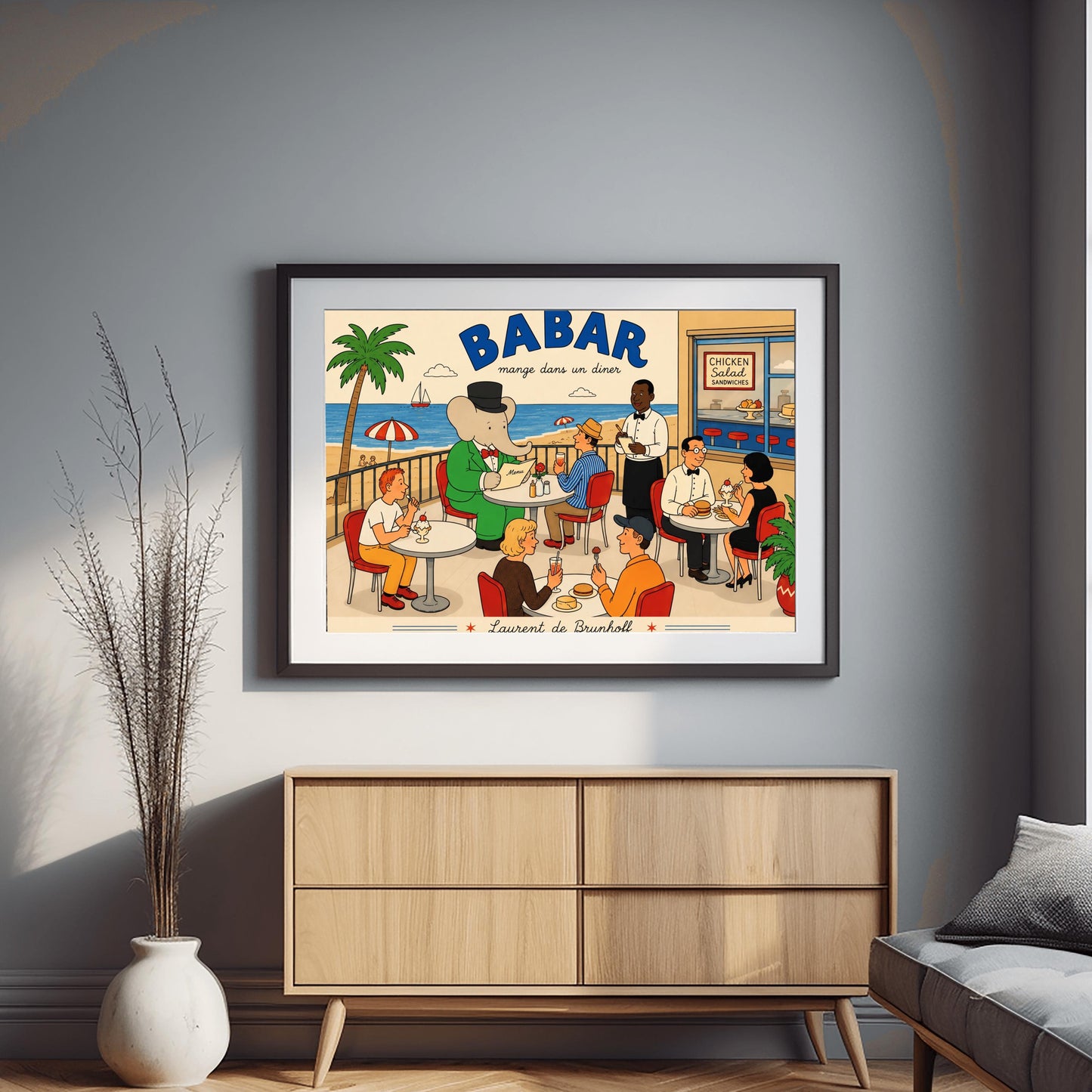A bright 1950s-style illustration poster titled "BABAR mange dans un diner" in bold blue and black script. The scene shows an outdoor diner balcony overlooking a sandy beach and blue ocean with a sailboat. On the left, the cartoon elephant King Babar sits at a round white table in a green suit and top hat, reading a menu. Several other patrons are seated at tables on red chairs eating burgers and ice cream sundaes, while a waiter in a bowtie takes notes.