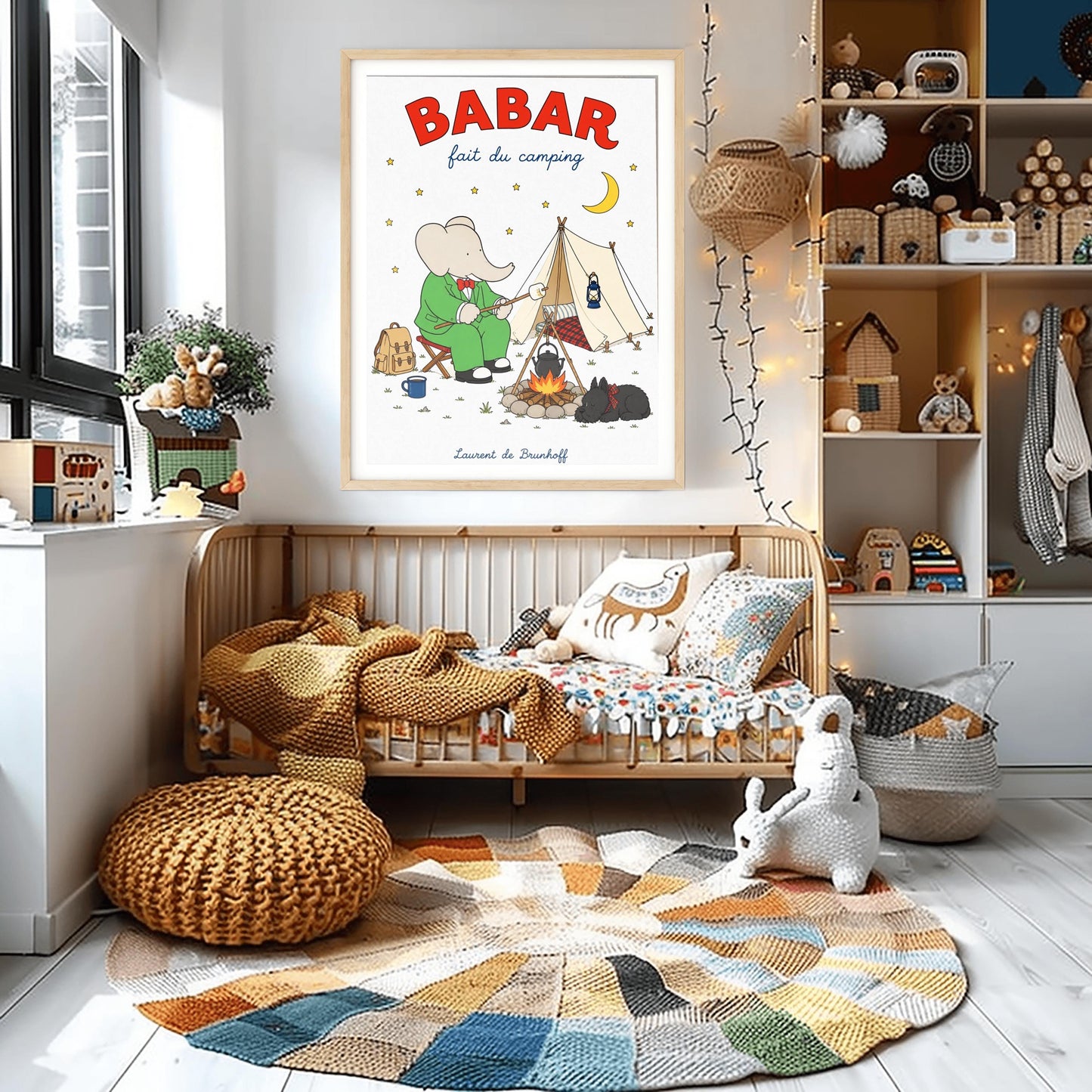 A vertical retro fine art exhibition poster titled "BABAR fait du camping" on a wide cream border. The top "BABAR" text is printed in a bold red font. The illustration shows an elephant in a green suit and red bowtie sitting on a stool by a campfire, toasting a marshmallow next to a white tent under a starry night sky with a yellow crescent moon. A small black dog in a plaid scarf sleeps nearby, and the name "Laurent de Brunhoff" anchors the bottom.