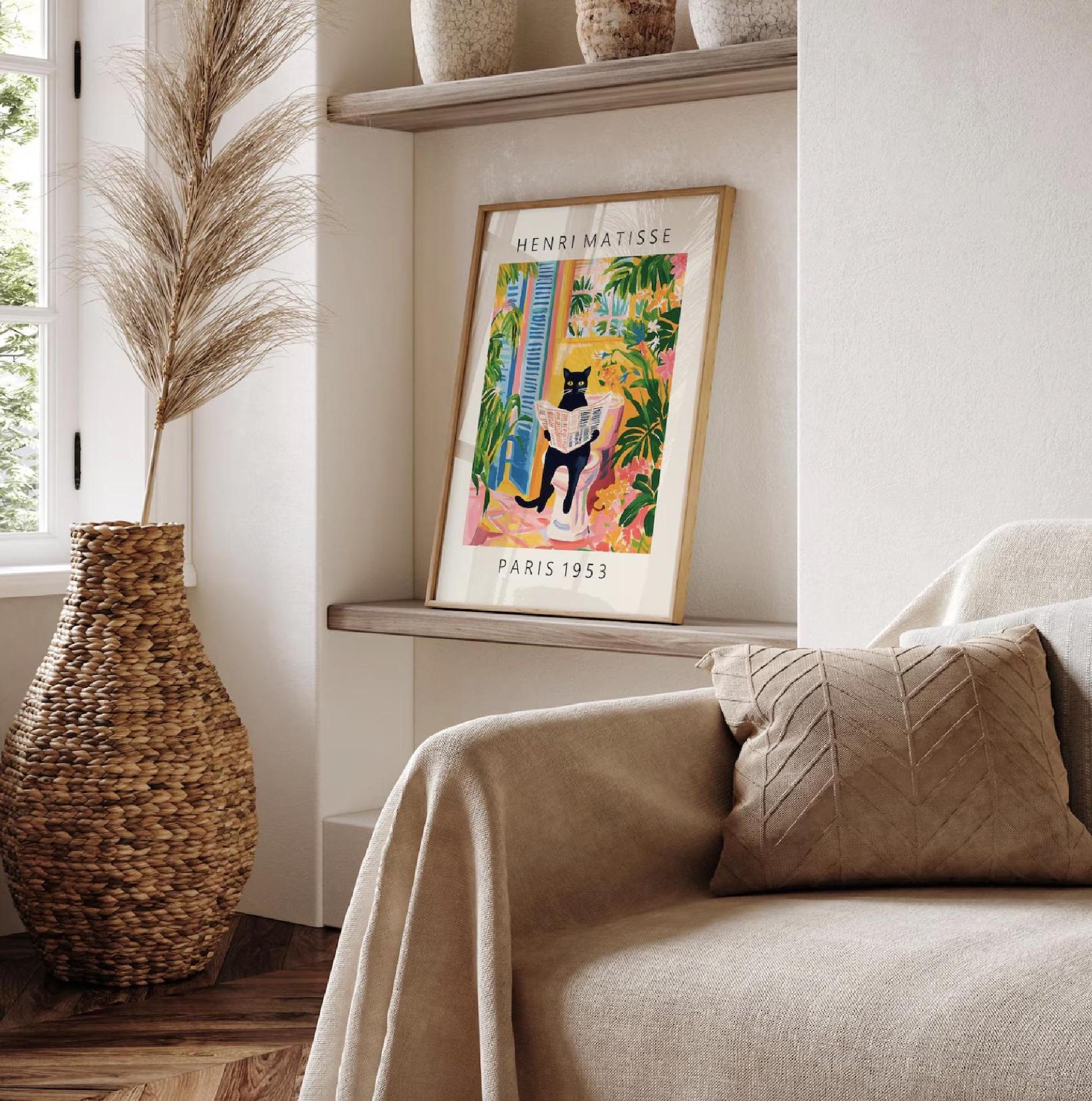 Framed artwork of a cat in a colorful setting on a shelf next to a couch with a pillow.