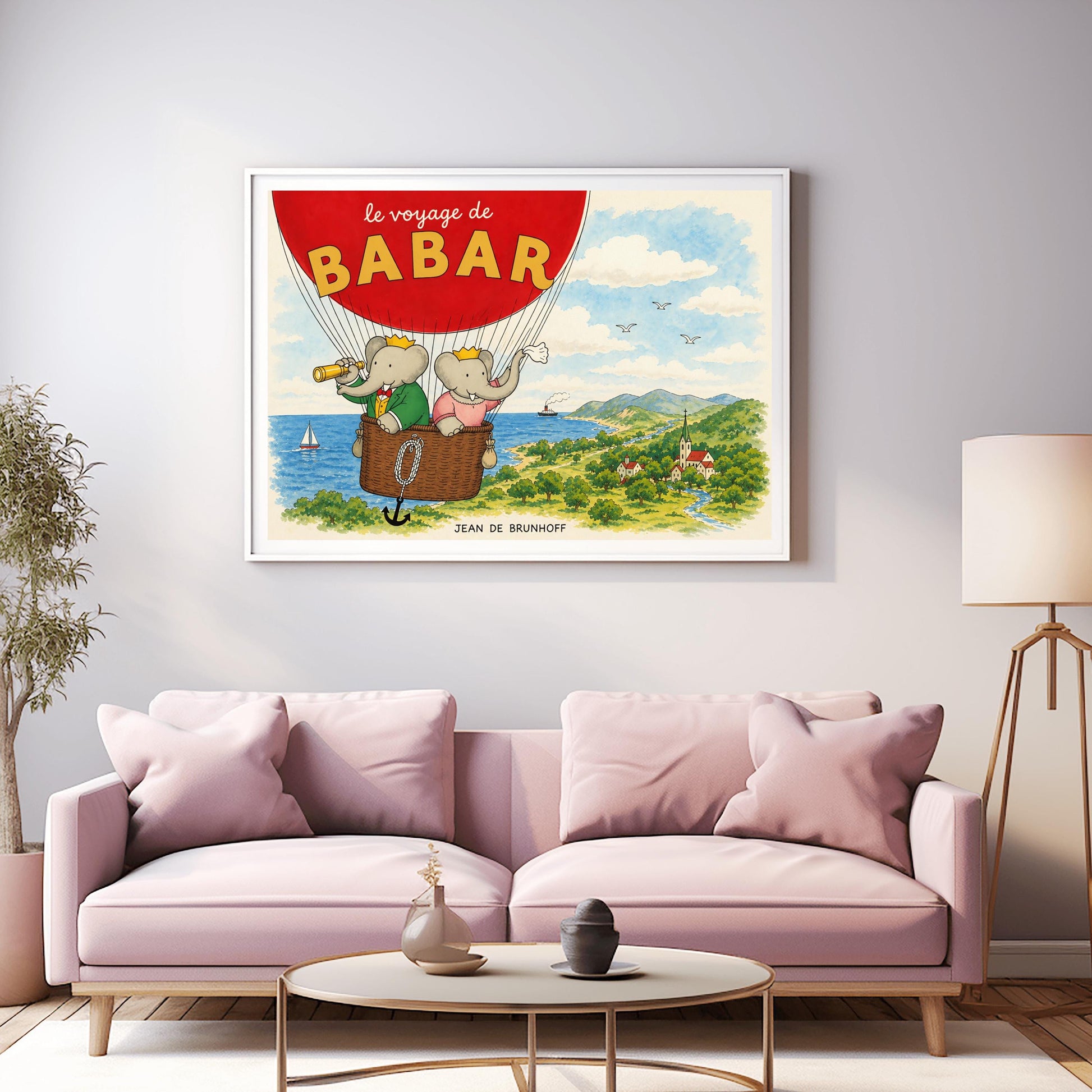A horizontal watercolor illustration from "Le Voyage de Babar." A large red hot air balloon dominates the top left, with its basket carrying King Babar and Queen Celeste. Babar, in a green suit and crown, looks through a telescope, while Celeste, in a pink dress and crown, waves a white cloth. They are floating over a lush green coastline with a blue ocean, a sailboat, and a small village nestled in a valley with a river and mountains in the distance.