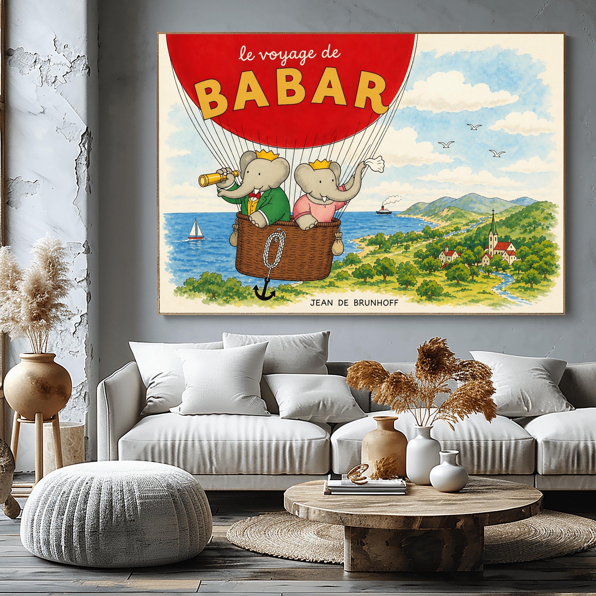 A horizontal watercolor illustration from "Le Voyage de Babar." A large red hot air balloon dominates the top left, with its basket carrying King Babar and Queen Celeste. Babar, in a green suit and crown, looks through a telescope, while Celeste, in a pink dress and crown, waves a white cloth. They are floating over a lush green coastline with a blue ocean, a sailboat, and a small village nestled in a valley with a river and mountains in the distance.