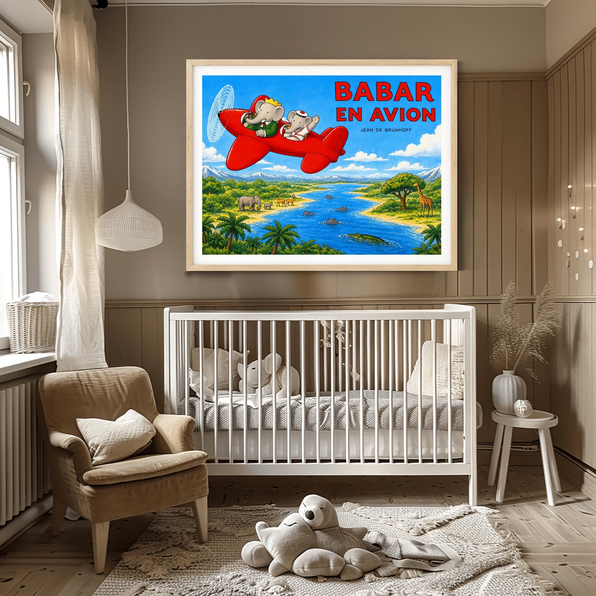 A horizontal watercolor-style illustration of Babar the Elephant flying a bright red propeller plane. Babar wears a green suit and crown, while a smaller elephant in a white sailor suit waves from the back seat. They fly over a vibrant safari landscape with a winding blue river filled with hippos and a crocodile. On the riverbanks are giraffes, antelopes, elephants, and palm trees. Snow-capped mountains rise in the distance under a blue sky. Large red text reads "BABAR EN AVION."