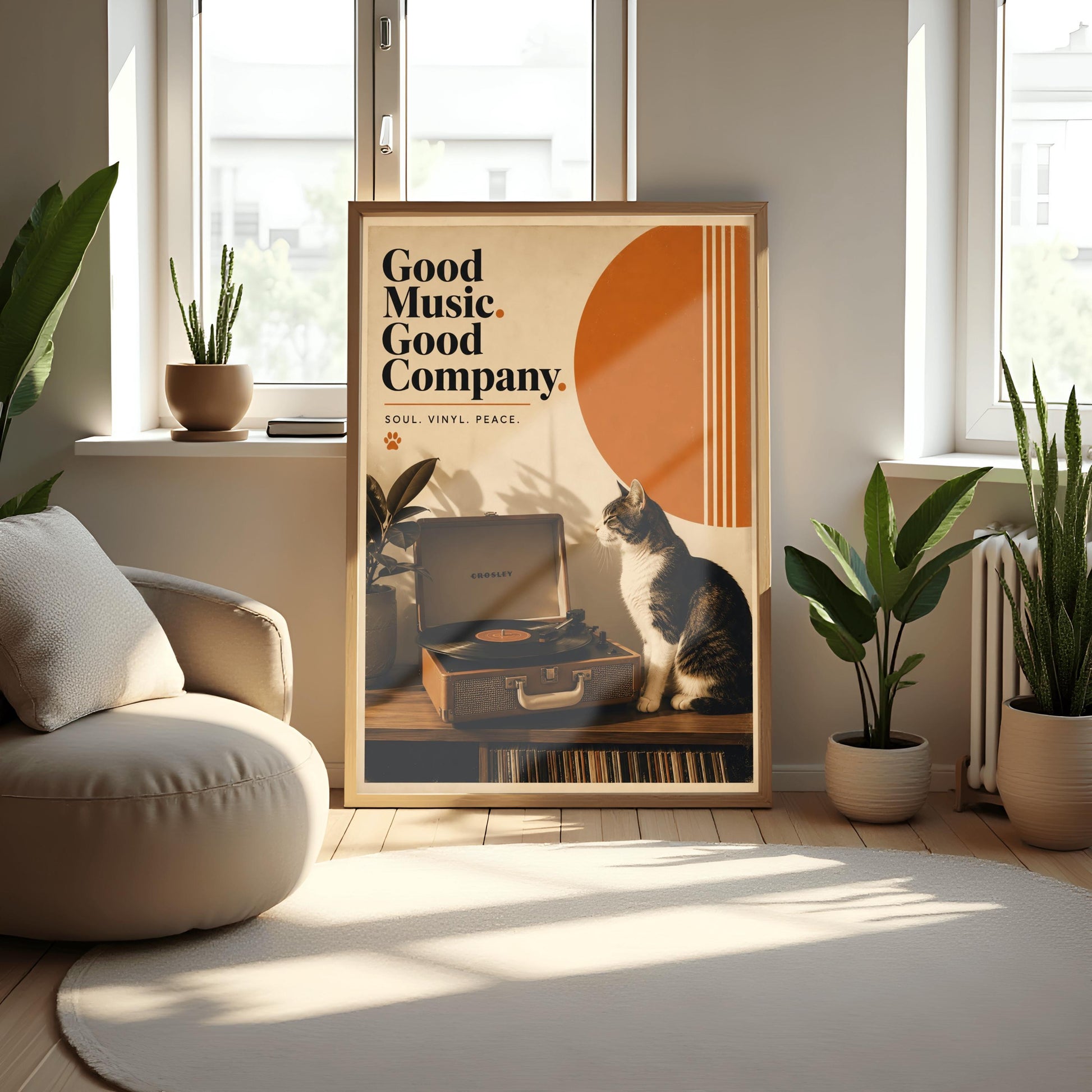 A vertical retro fine art poster titled "Good Music. Good Company." on a wide cream border. The design features a bold black serif heading on the left above the text "SOUL. VINYL. PEACE." and a small orange paw print. In the central artwork, a black and white tuxedo cat sits contentedly next to an open tan Crosley record player spinning a vinyl record. A large orange sun shape with white vertical stripes and a potted rubber plant decorate the background.