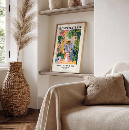 Framed Henri Matisse art print of a tabby cat reading a newspaper in a tropical setting.